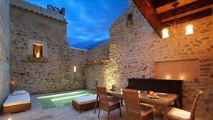 An outdoor patio with stone walls, a dining table with chairs, a small pool, and a fireplace. - Mallorca One by Balearic Villas (Pollensa)