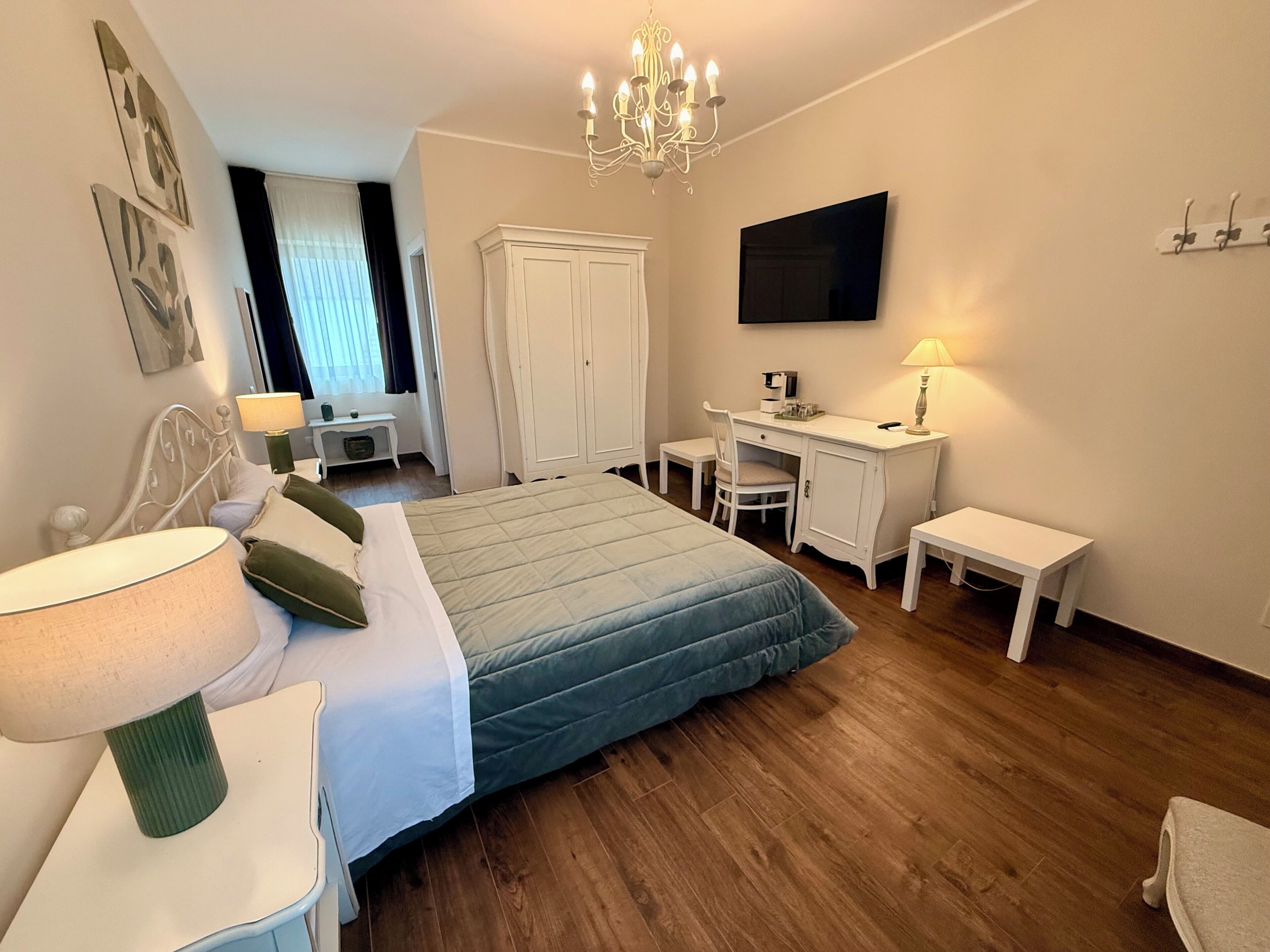 Un dormitorio con cama, escritorio, silla y televisor en la pared.