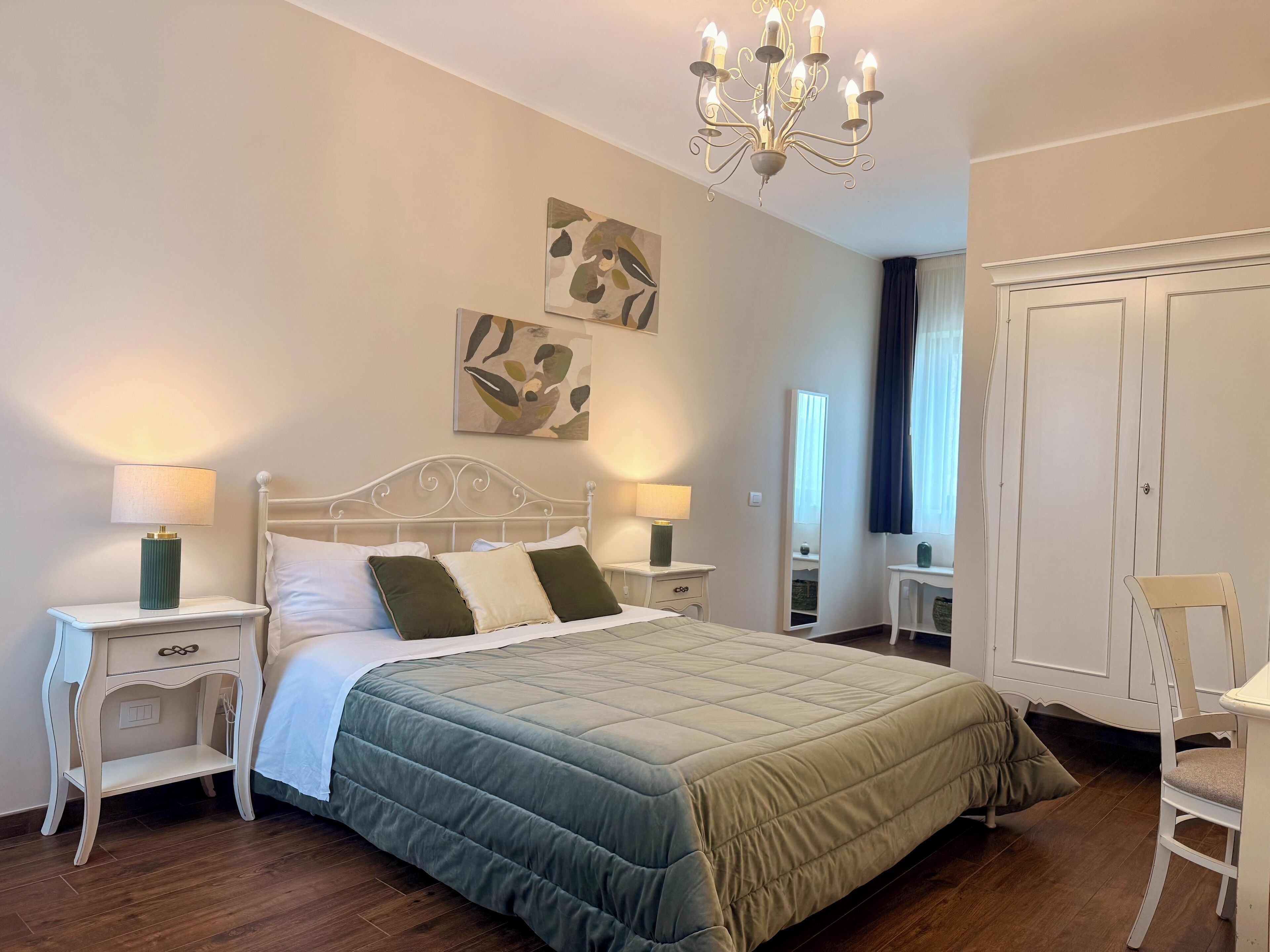 Un dormitorio ordenado con una cama grande, dos mesitas de noche con lámparas, un espejo y un armario.