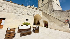 A courtyard with stone walls, wooden benches, and a tower. - Masseria Torre Spagnola  (Matera)