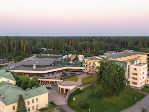 A hotel with a central courtyard, multiple buildings, and a surrounding forest.