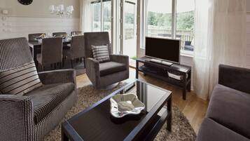 A living room with a sofa, armchairs, a coffee table, a TV, and a dining area with a table and chairs.