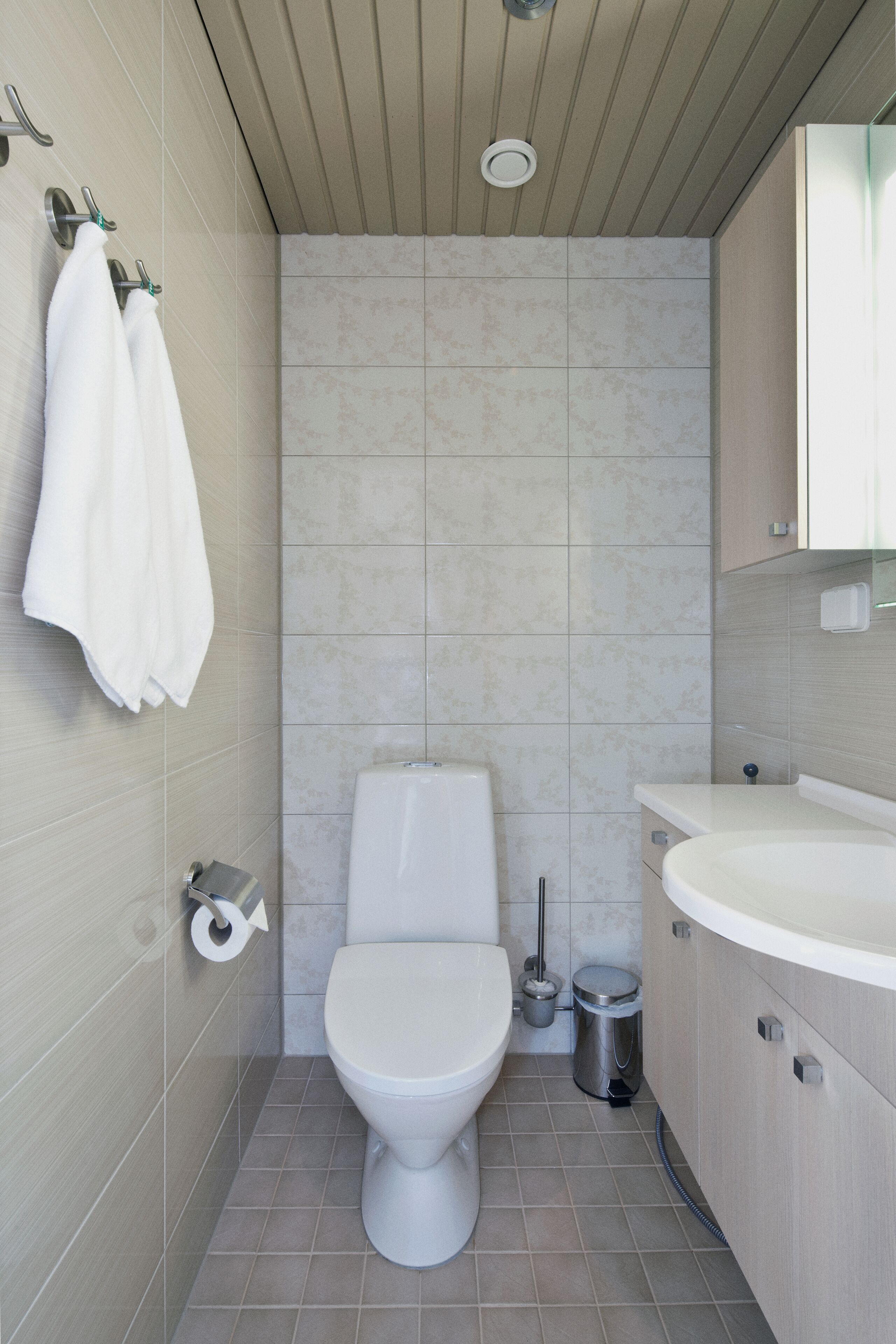 A modern bathroom with a toilet, sink, and towel rack.