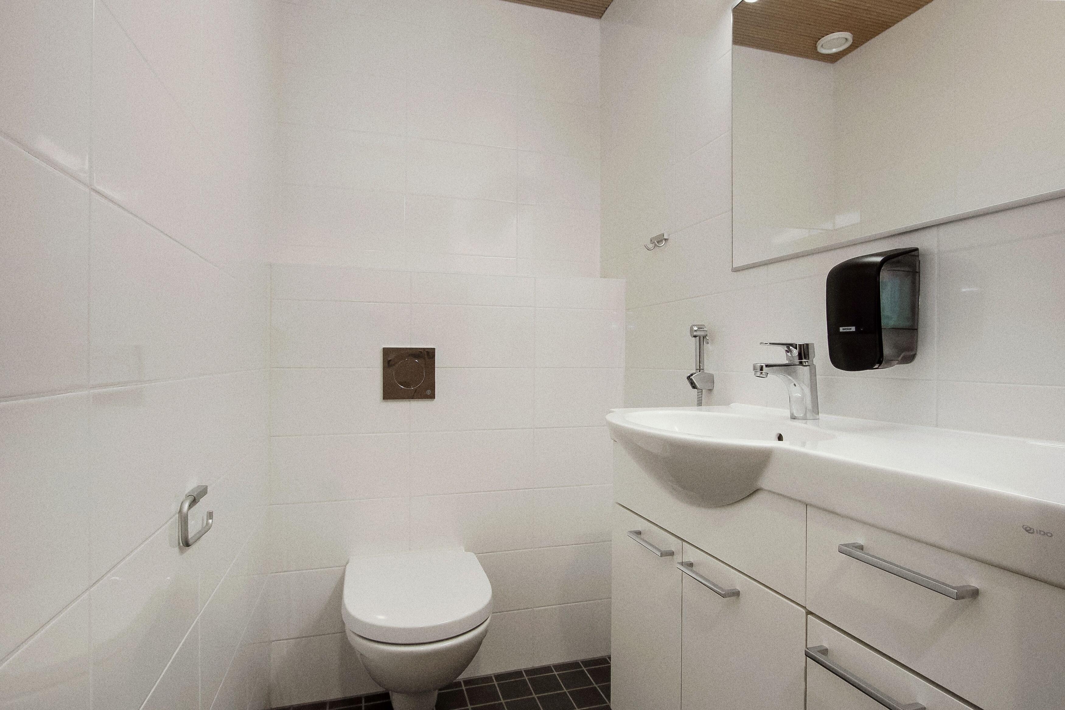 Un baño moderno con inodoro, lavamanos y espejo.