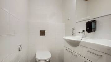 Un baño moderno con inodoro, lavamanos y espejo.