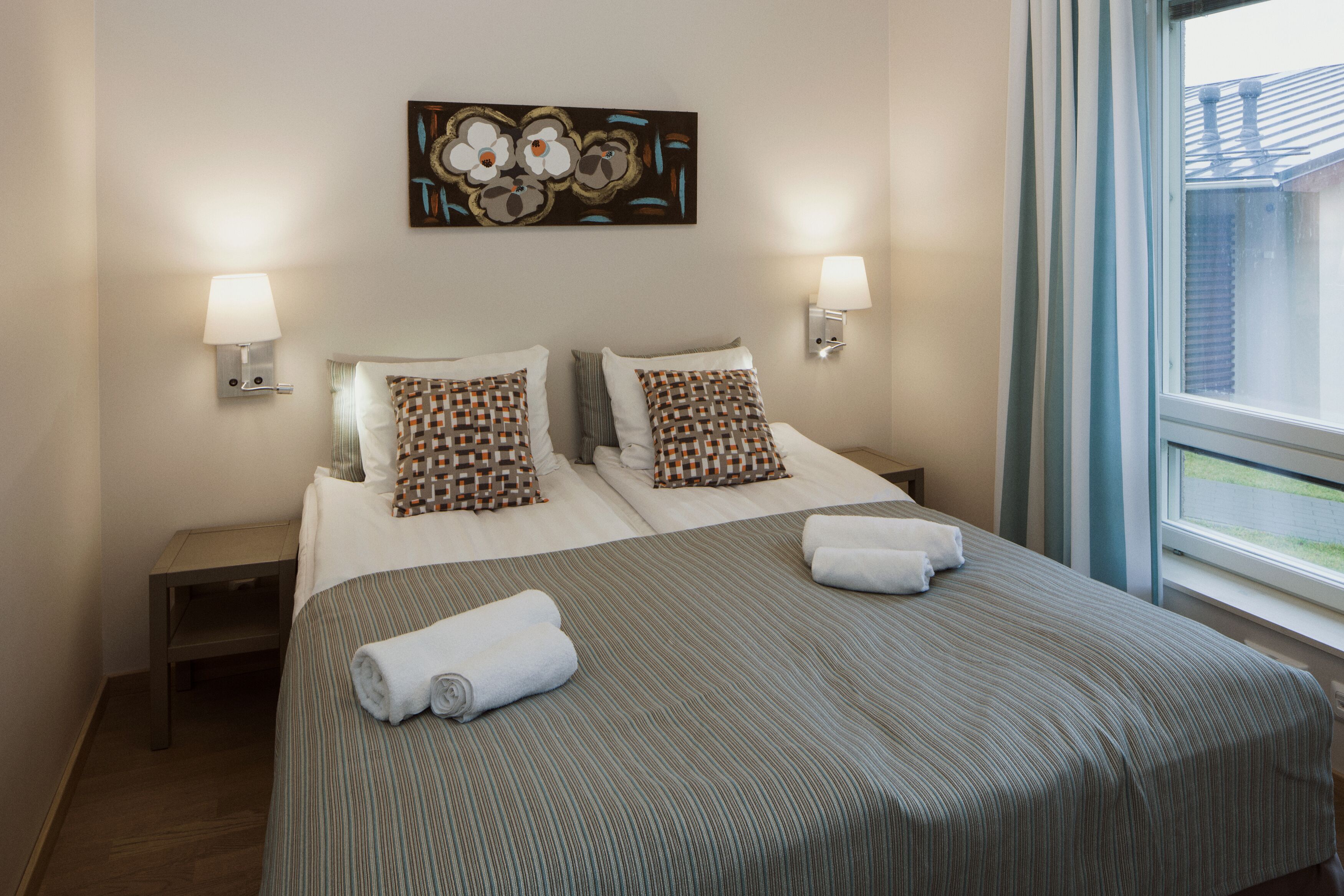 Habitación de hotel con dos camas, un cuadro en la pared y una ventana con vistas.