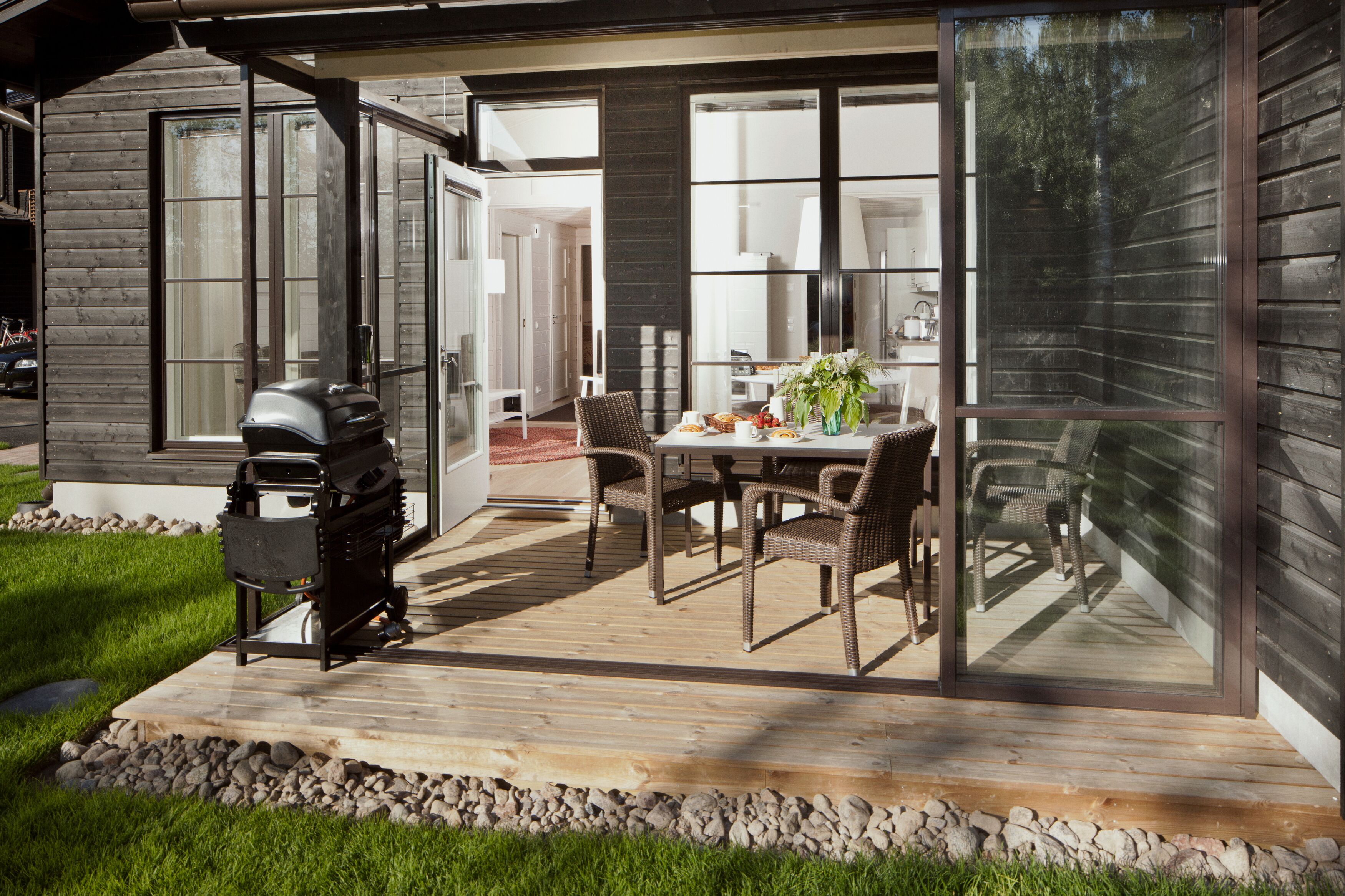 A patio with a grill, dining table, and chairs.