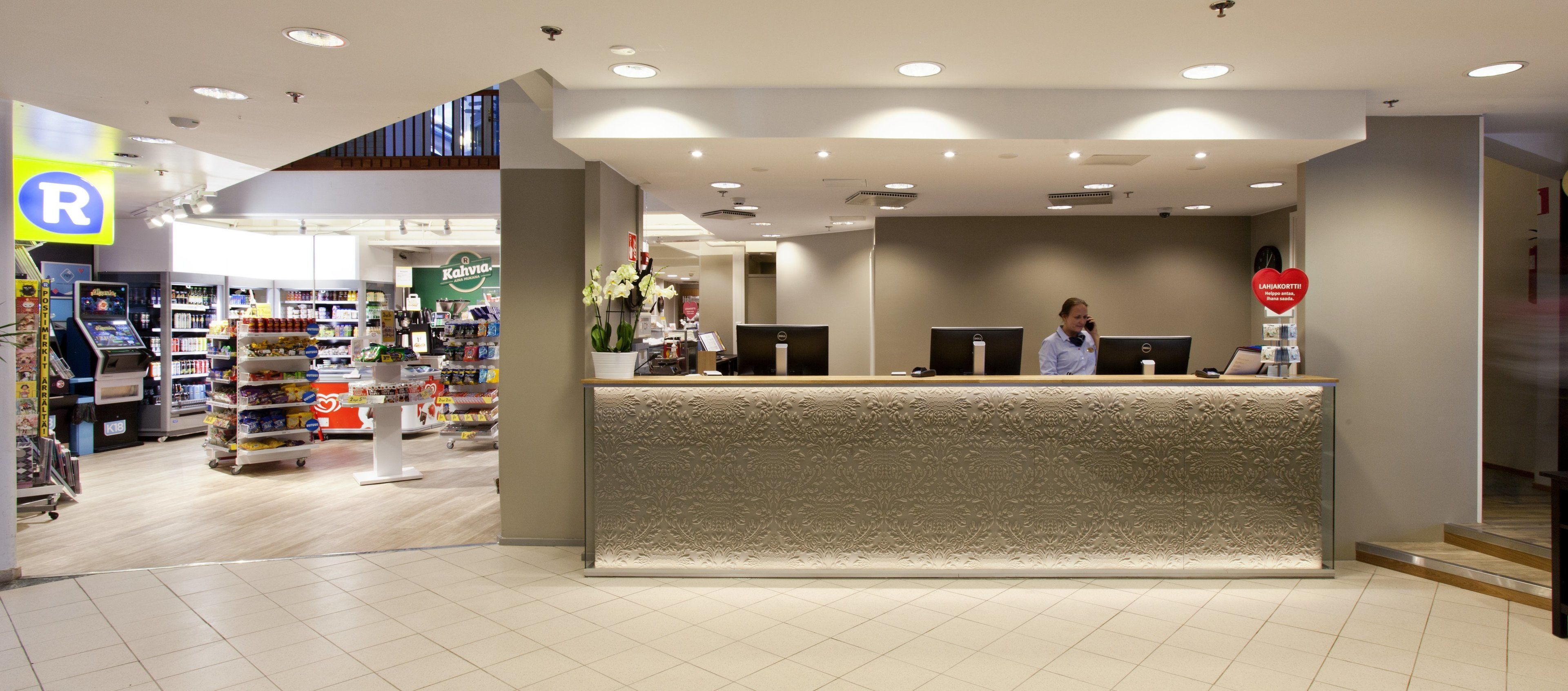 Een receptiebalie met een bloemenprint, een apotheek, en een zichtbaar 'R'-teken dat een apotheek aangeeft.