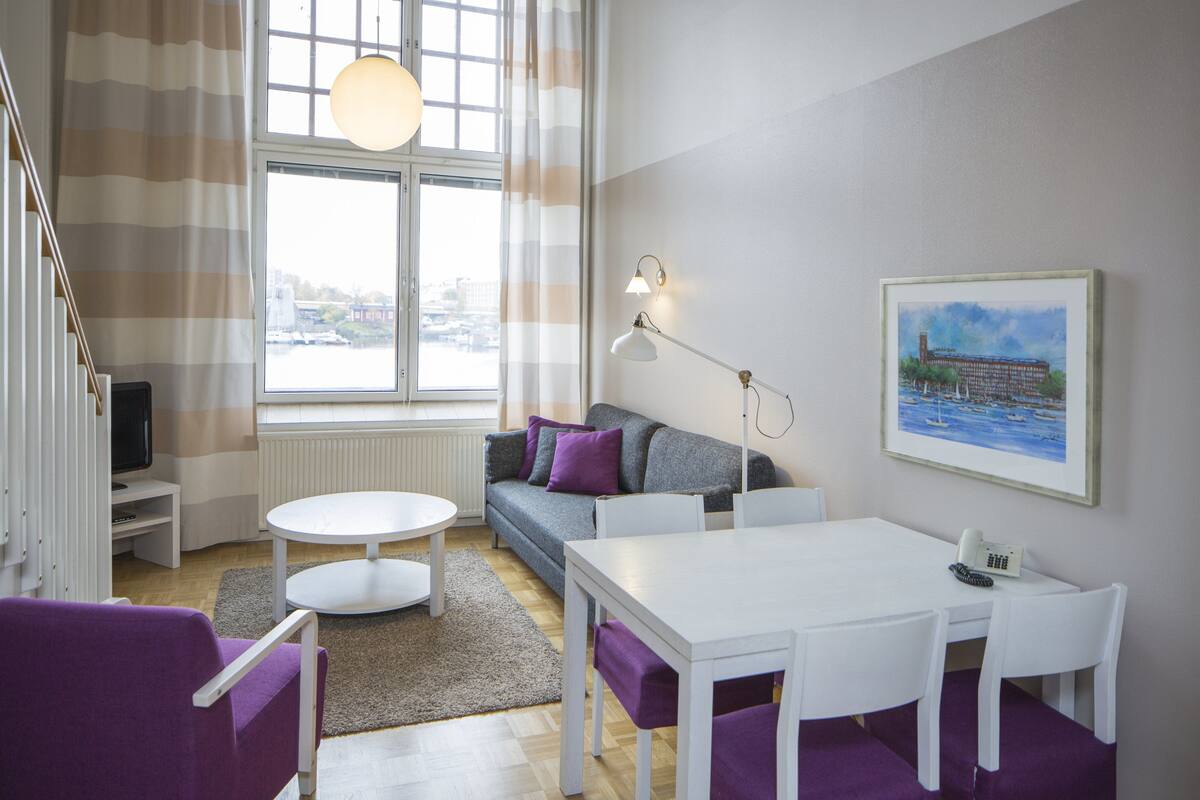 A modern living room with a sofa, a dining table, and a TV.