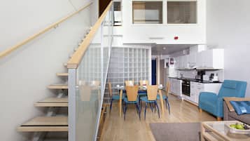 A modern apartment with a staircase, a dining area, a kitchen, and a living room.