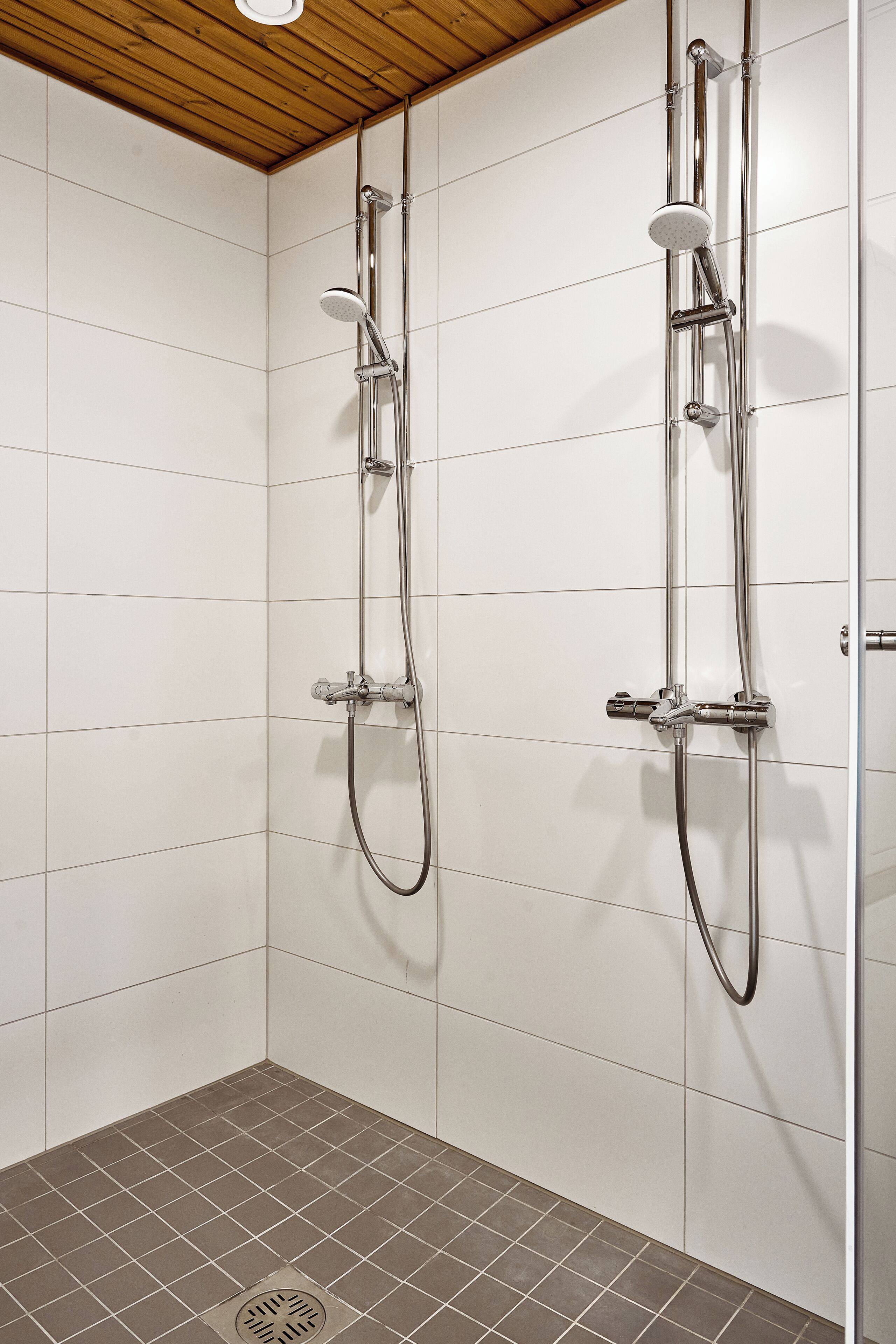 A shower with chrome fixtures and a tiled floor.