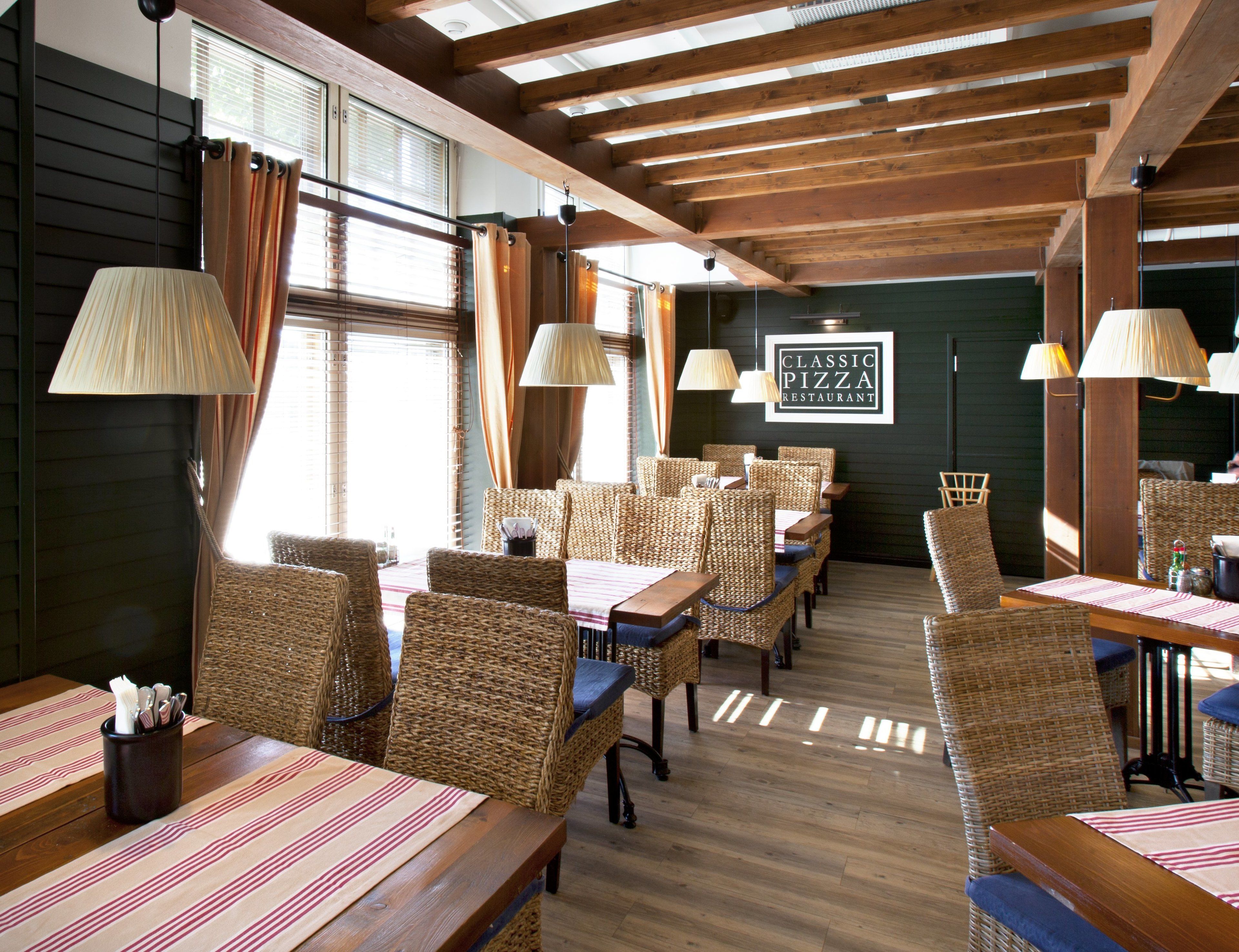 Een restaurantinterieur met rieten stoelen, houten tafels en hanglampen.
