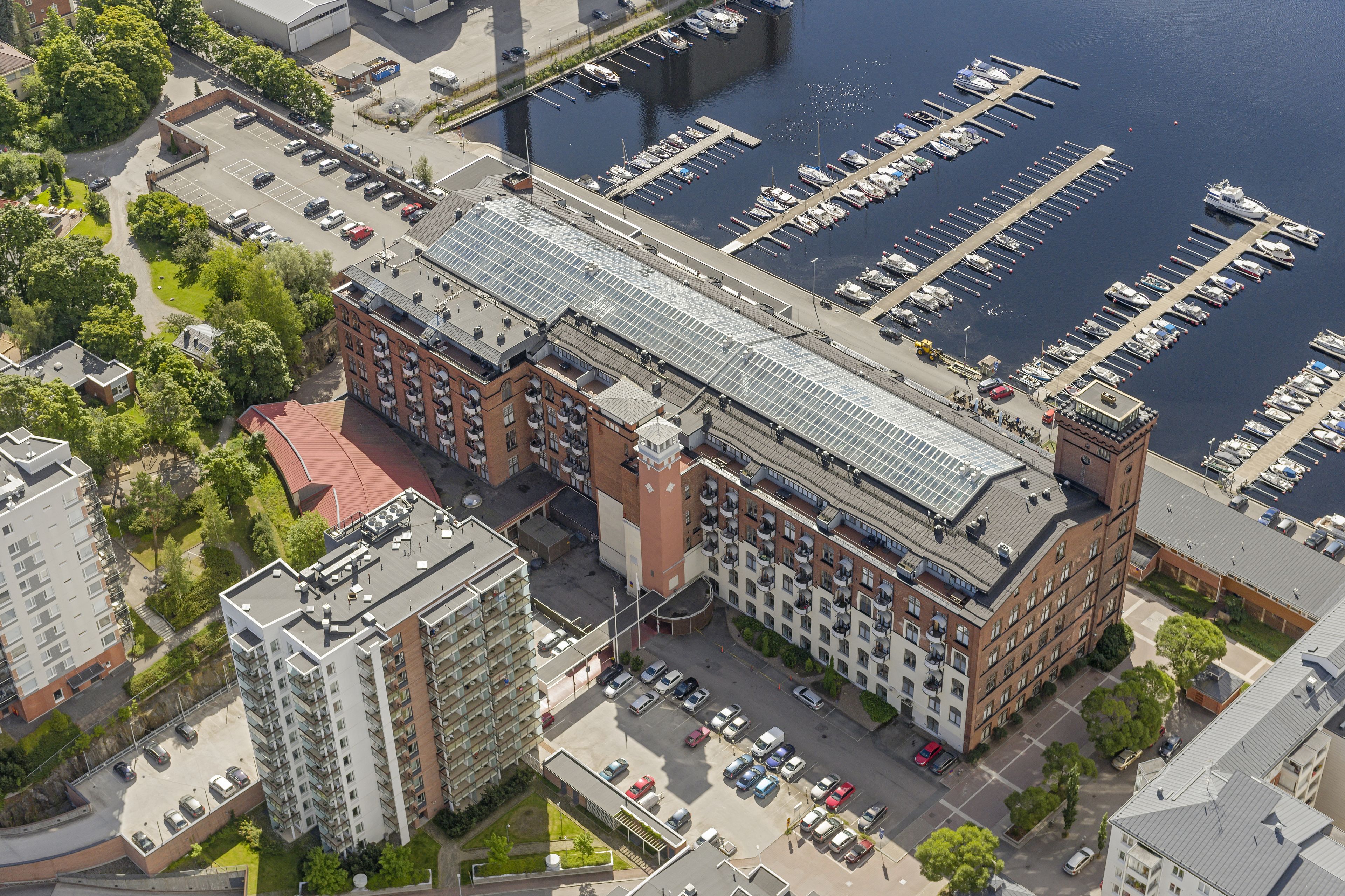An aerial view of a marina with docked boats, a parking lot, and adjacent residential buildings.