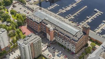 An aerial view of a marina with docked boats, a parking lot, and adjacent residential buildings.
