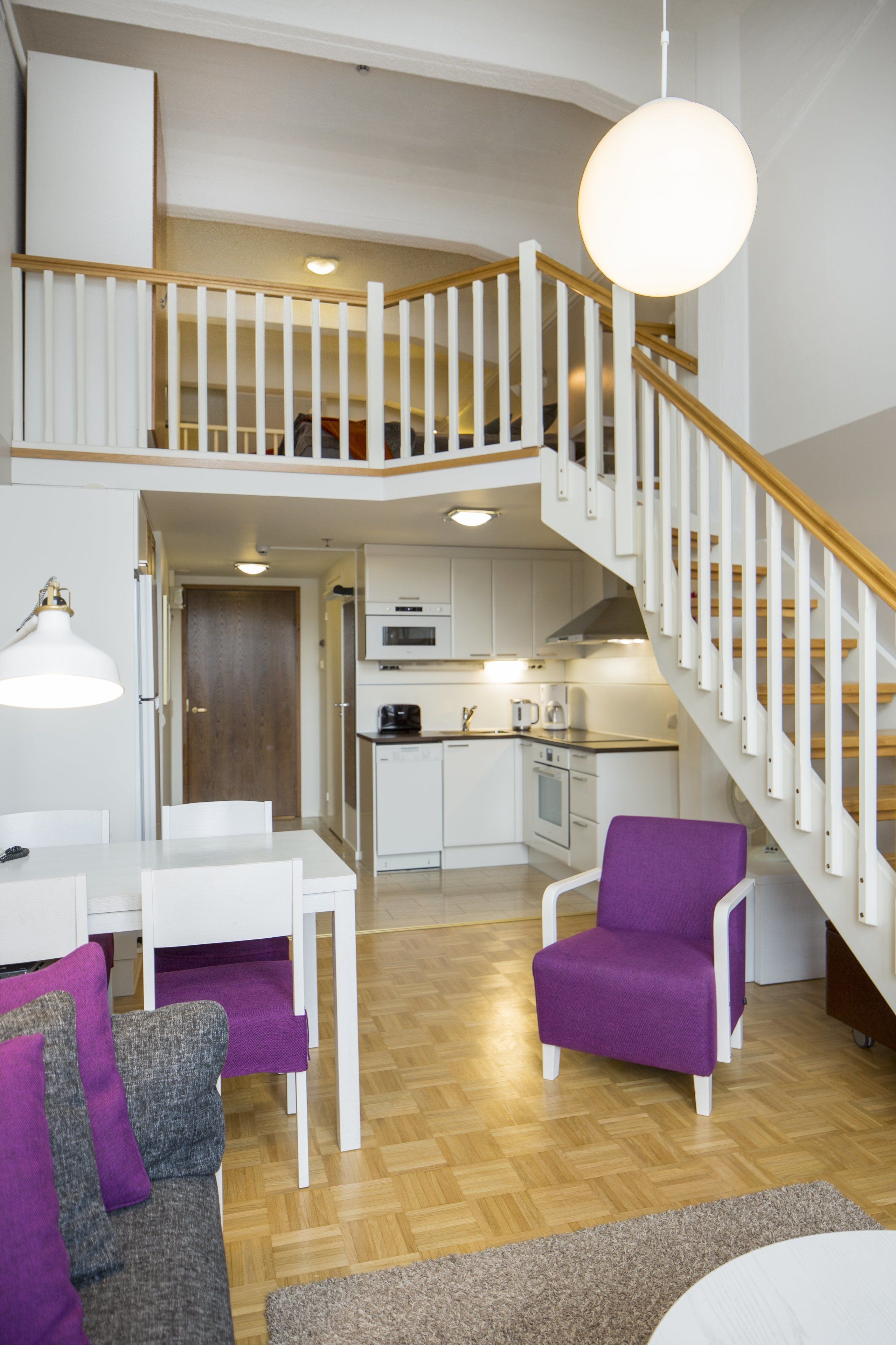 Un apartamento moderno con cocina, comedor y una escalera.