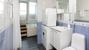 Pieni kylpyhuone, jossa on pesukone, pesuallas ja wc.