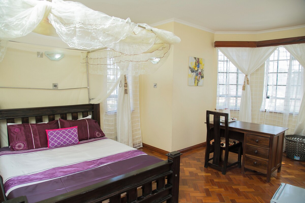 A bedroom with a bed, a desk, and a chair.