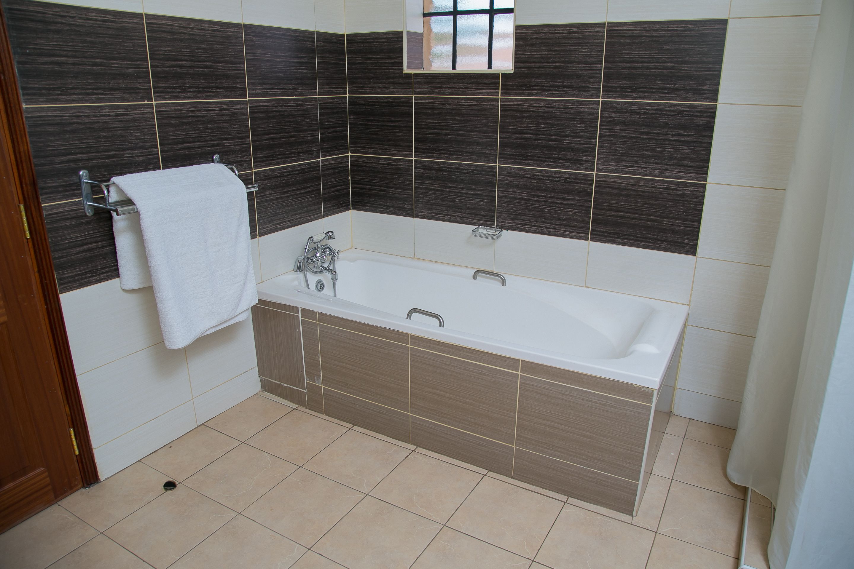 A bathroom with a bathtub, a towel rack, and a window.