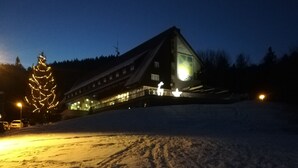 Ett snötäckt landskap med en byggnad som har en stor glasfasad och ett sluttande tak.