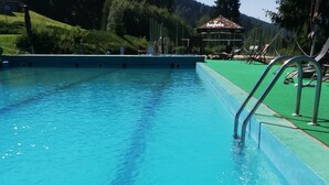 En klarblå pool med en metallstege på höger sida.