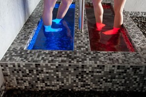 A tiled pool area with two distinct sections, one illuminated with blue light and the other with red light.