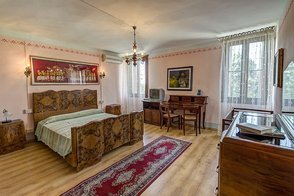A bedroom with a wooden bed, a desk, and a television.