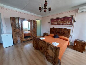 A bedroom with a wooden bed, a mirror, a white refrigerator, and a painting on the wall. - Bordeghina B&B in Farmhouse (Pontecchio Polesine)