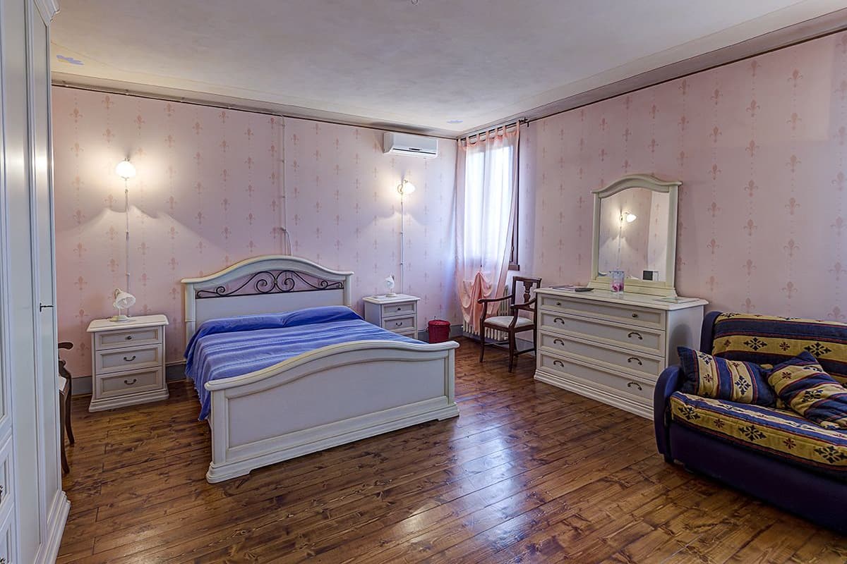 A bedroom with a bed, dresser, chair, and a sofa.