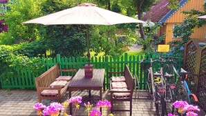 A patio with a table and chairs, a bicycle, and a green fence.