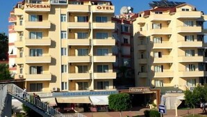 Un hotel de diverses plantes amb balcons, panells solars i l'entrada a un centre comercial.