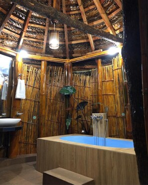 A bathroom with a wooden ceiling, bamboo wall panels, a sink, and a bathtub. - Tea Cabins (Ella)