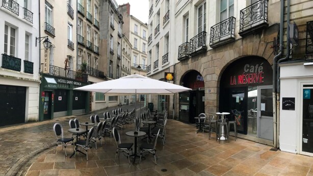 A café with outdoor seating, a white umbrella, and a sign for 'La Réserve'. - Hôtel Saint Patrick Cœur de NANTES (Nantes)