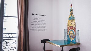 A room with a mural of a colorful building, a table, and chairs. - Hôtel Saint Patrick Cœur de NANTES (Nantes)