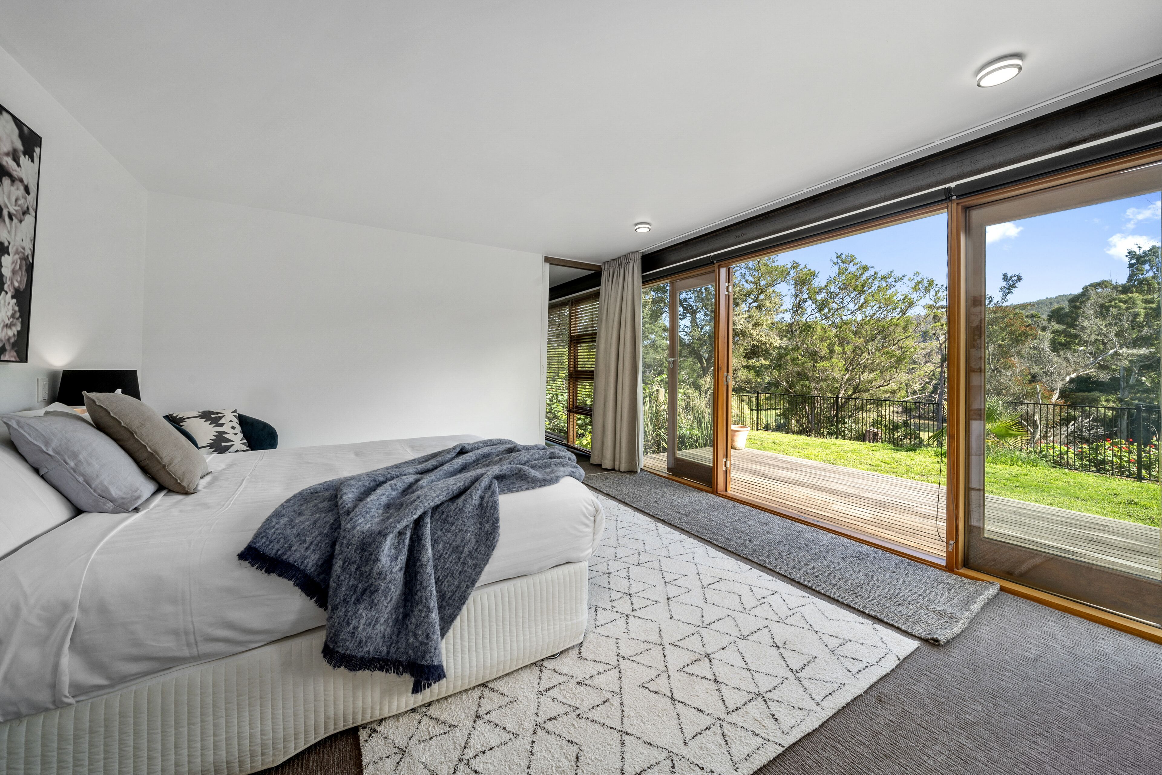 Un dormitorio moderno con una cama grande, vistas al exterior y una puerta corrediza de vidrio.