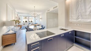 A modern kitchen with a central island, built-in appliances, and a dining area with a chandelier. - Luxury Blue River by Mmega (Firenze)