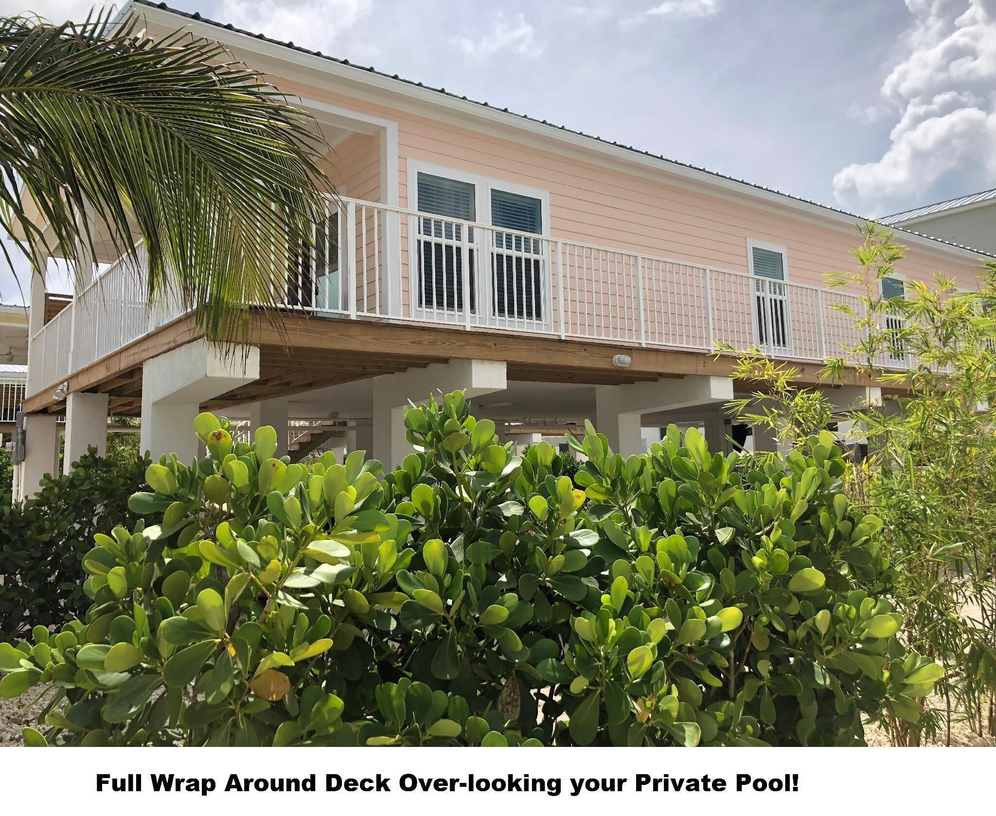 A two-story house with a full wrap-around deck overlooking a private pool.