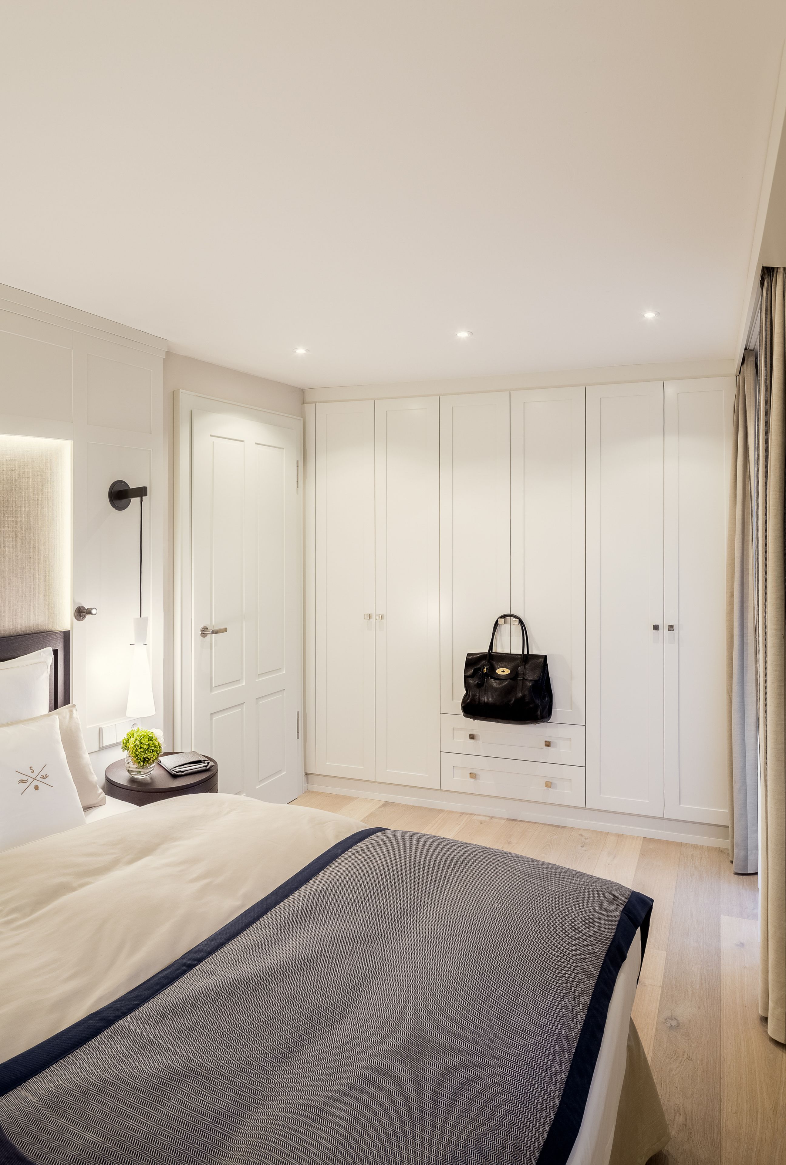A bedroom with a bed, a wardrobe, a nightstand, and a lamp.