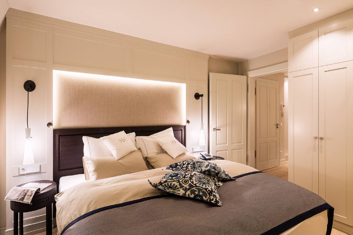 Una habitación de hotel con una cama grande, una mesita de noche con lámpara y un armario.