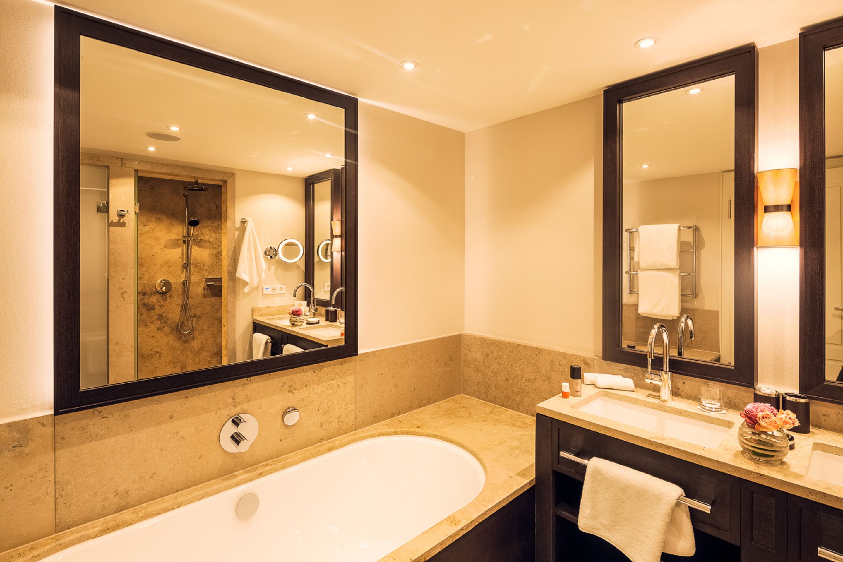 A modern bathroom with a large bathtub, a double sink vanity, and a large mirror.