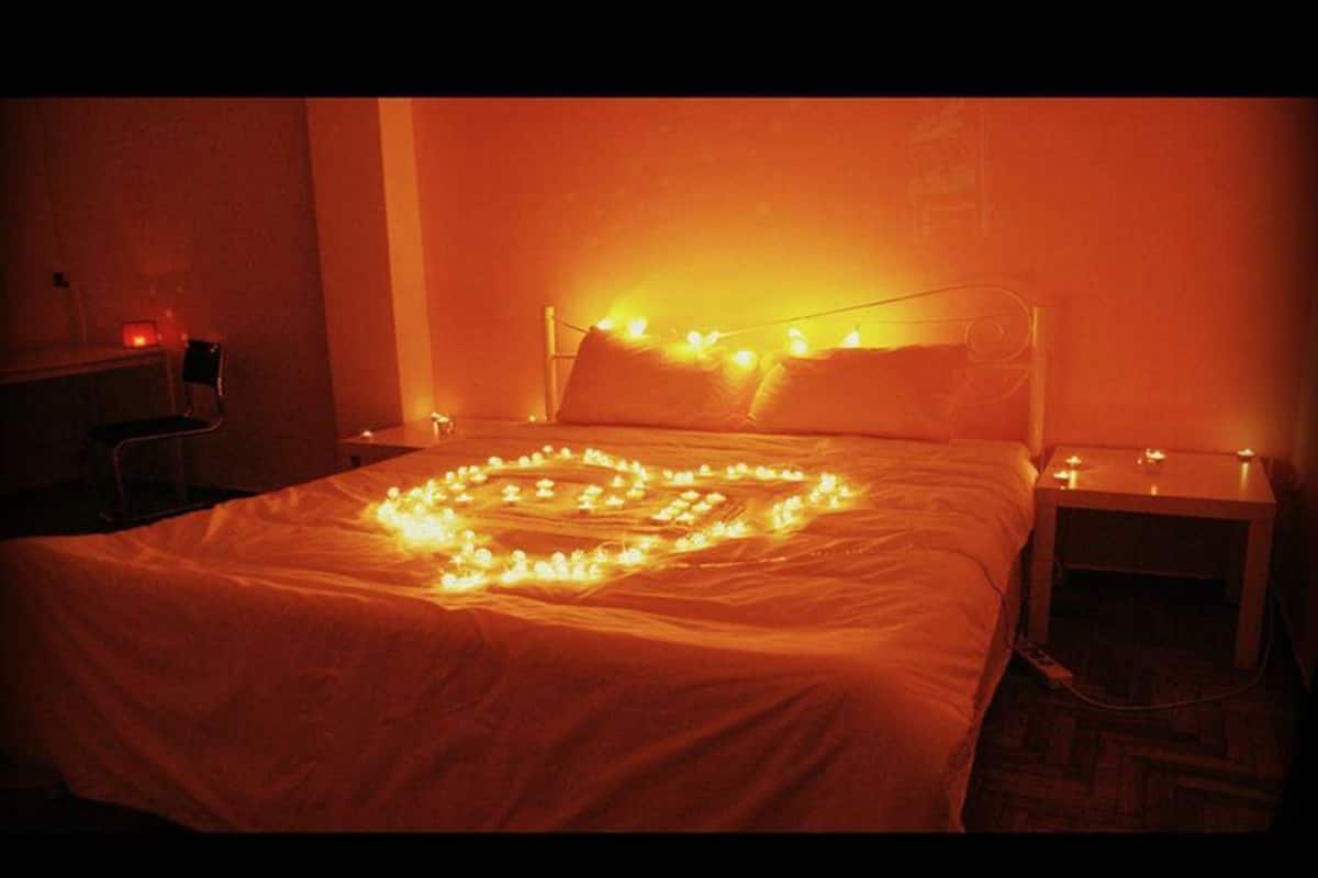 Una cama con una decoración de luces en forma de corazón sobre el edredón.