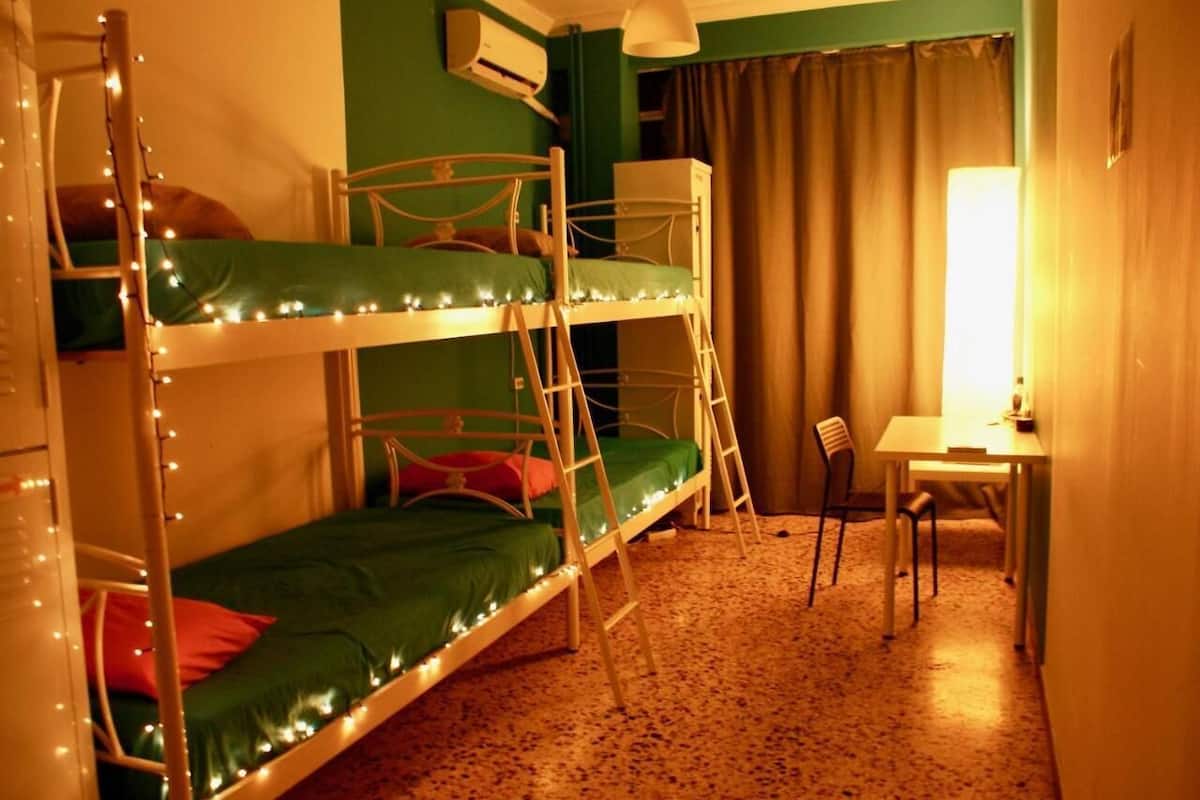 Una cama litera con luces, un escritorio y una silla en una habitación con paredes verdes y alfombra marrón.