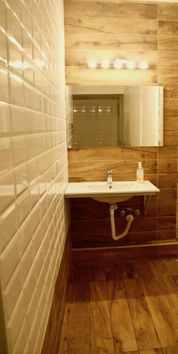 Un baño con tocador de madera, lavabo blanco y espejo.