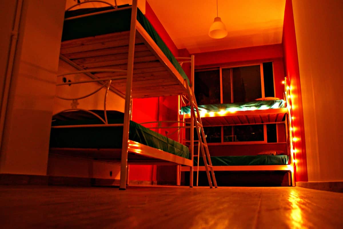 Una habitación con literas y una escalera, una ventana y una lámpara colgante.