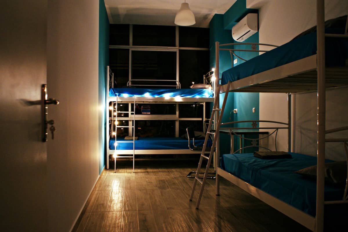 Un dormitorio con literas, suelo de madera y ventana con cortinas.