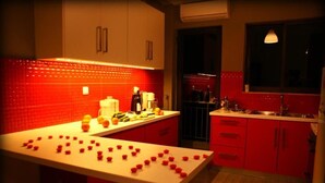 Cocina con armarios rojos, encimera blanca y ventana con lámpara colgante.