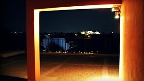 Vista nocturna a través de un umbral, con un paisaje urbano de fondo.