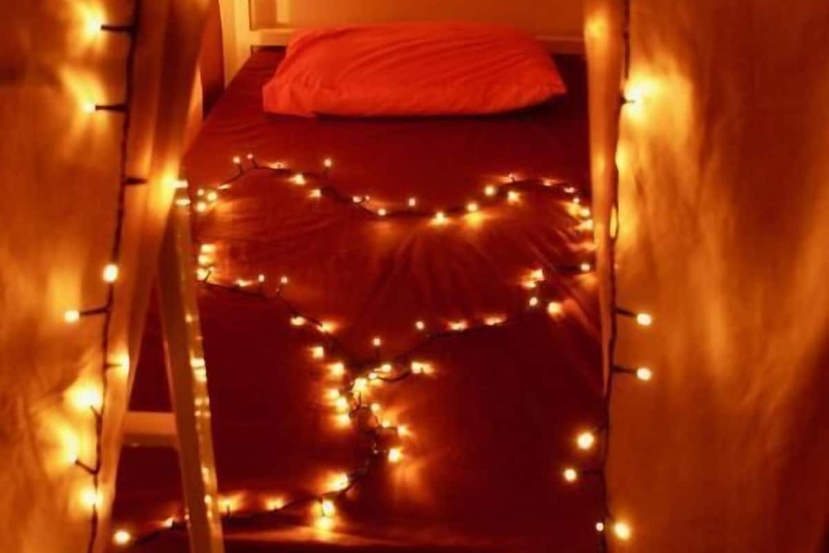 Una cama litera con un almohadón rojo, rodeada de luces de cadena.