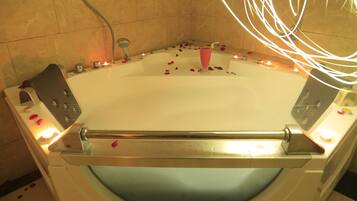 A bathtub with rose petals and candles, indicating a romantic setting.