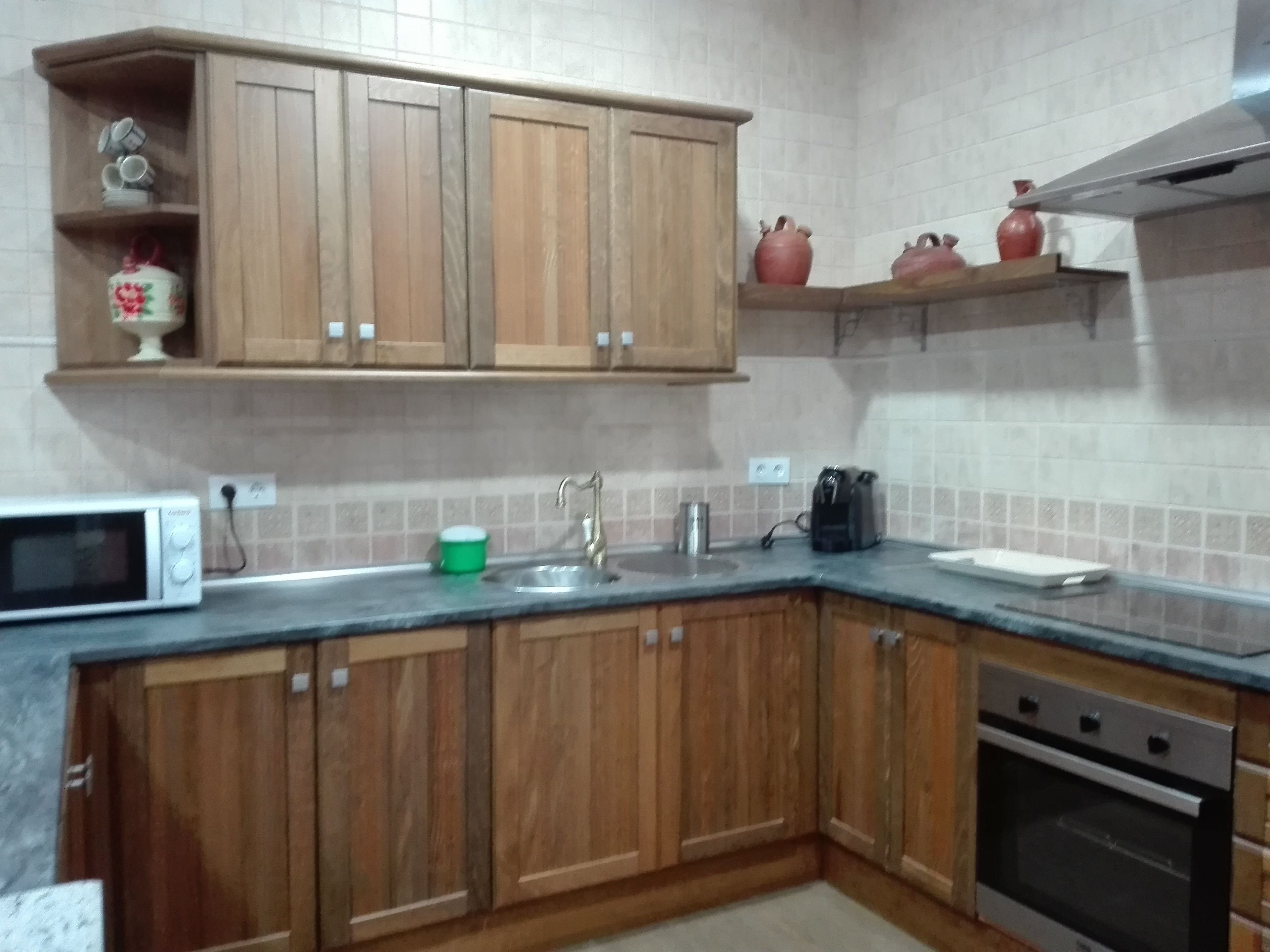 A kitchen with wooden cabinets, a microwave, a sink, a coffee maker, and a stove.