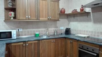 A kitchen with wooden cabinets, a microwave, a sink, a coffee maker, and a stove.